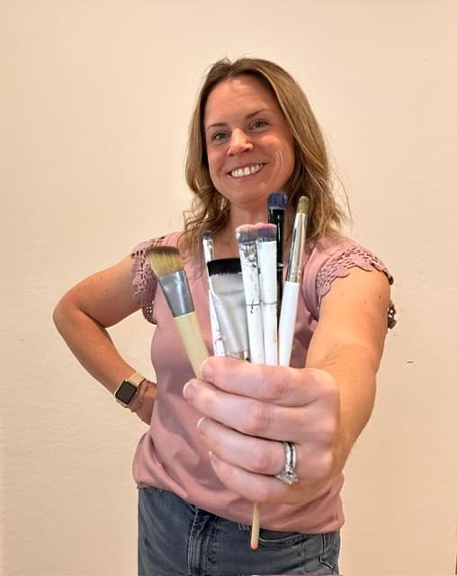Hannah holding a handful of paintbrushes